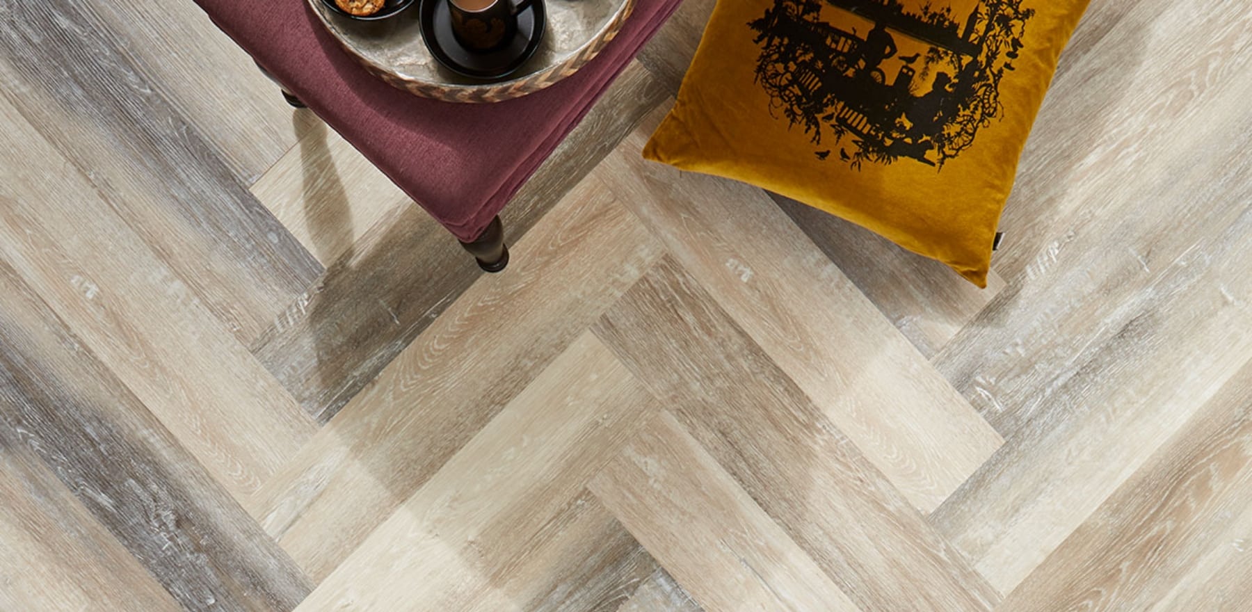 A bird's-eye view of Click LVT Flooring with a yellow pillow and burgundy stool visible at the top of the frame.
